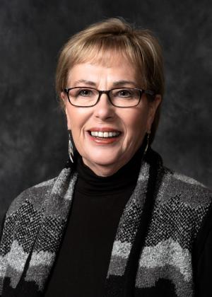 Woman with glasses and short, blonde hair. 